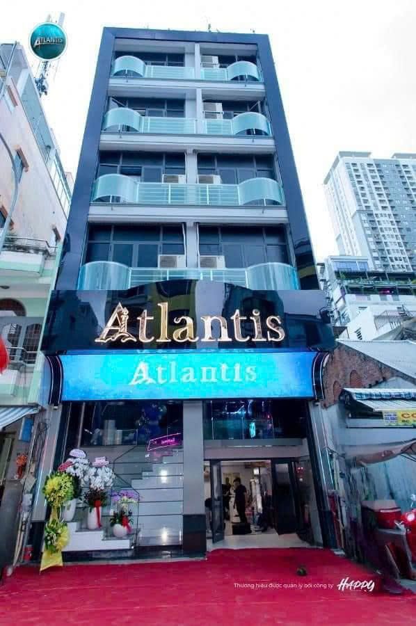 ATLANTIS KTV 胡志明第一郡門頭，金色 Atlantis 招牌與藍色海浪 LED 燈箱，紅毯入口