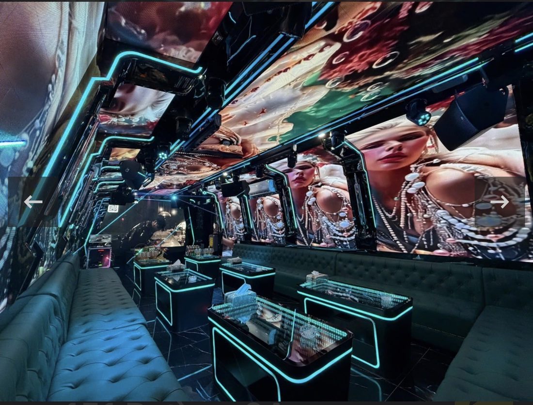 DRAGON PALACE KTV 長條形包廂，牆面與天花全是 LED 屏放珠寶人像畫面，青綠燈帶勾邊，墨綠絨面鈕扣長沙發