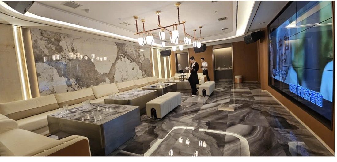 金爵會所長廳包廂：整幅天然石材背景牆、線性吊燈、灰白大理石地面與奶白長沙發