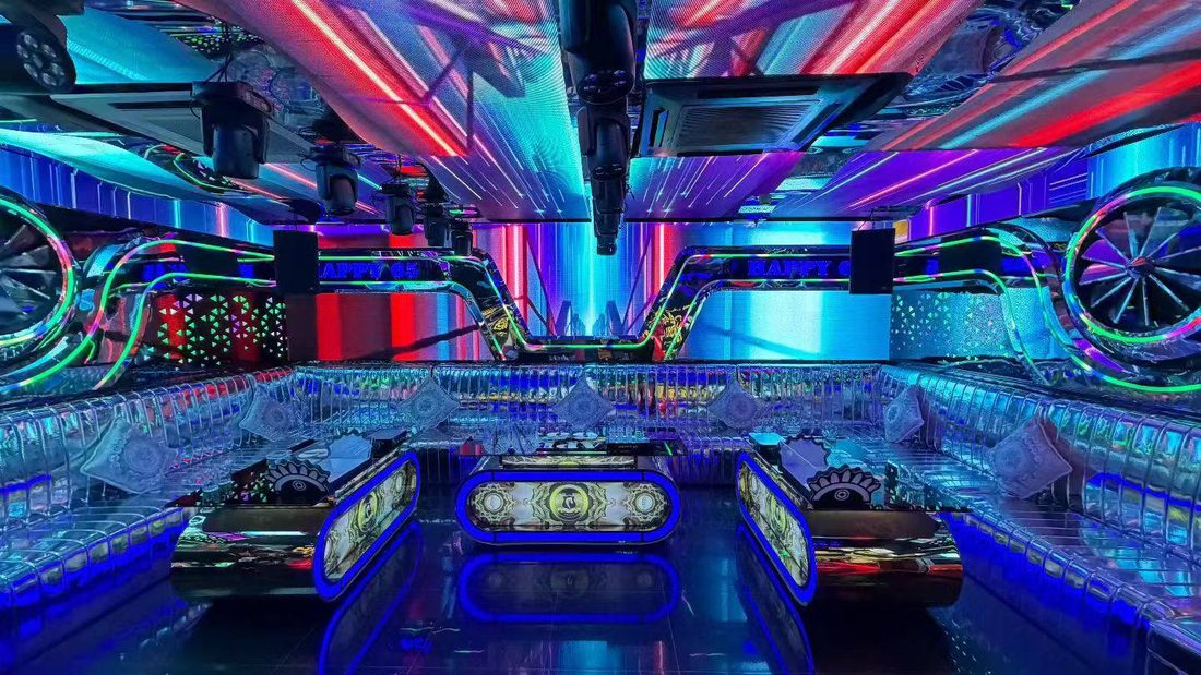 HAPPY 65 KTV 賽博車輪包廂：天花 LED 條屏斜掃光，兩側巨型發光車輪，三張膠囊形茶几