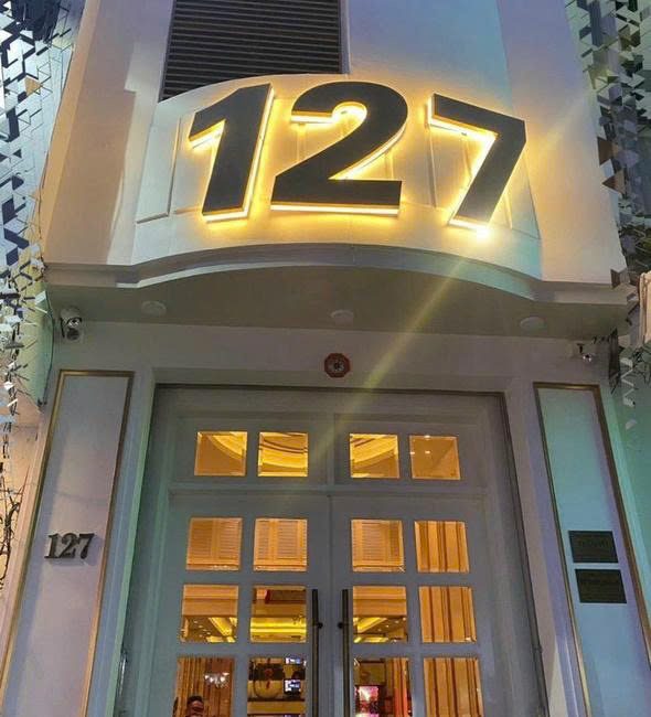 NEW 127 KTV 門頭：白色門面上金色背光立體 127 數字招牌與白色法式對開玻璃門
